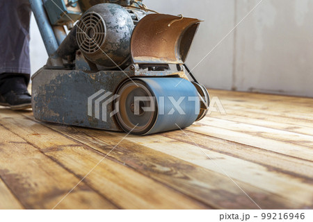 Worker polishing parquet floor with grinding machine. Worker polishing parquet floor with grinding machine. 99216946