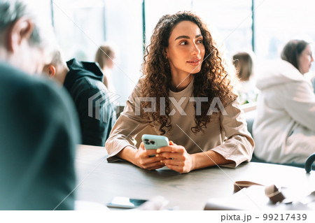 Young woman in a cafe reading a message from her mobile phone 99217439