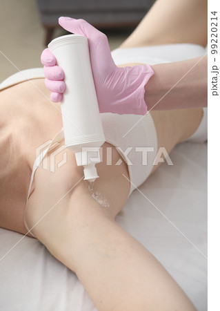 beautician applying guide gel on client's armpits. ipl laser epilation procedure. getting smooth skin in a salon. vertical size  99220214