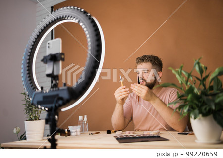 Portrait bearded man making vlog review cosmetics product and channel recording video make up tutorial making at home - Online influencer guy and social media market live steaming concept 99220659