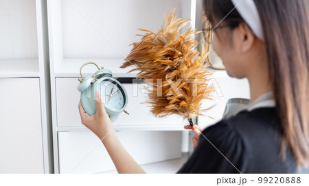 Housewife holding a dusting brush to clean things Pillows, rugs and other things in the living room, Big cleaning, Daily routine ,Removes germs and dirt and deep stains, Clean up on weekends. 99220888