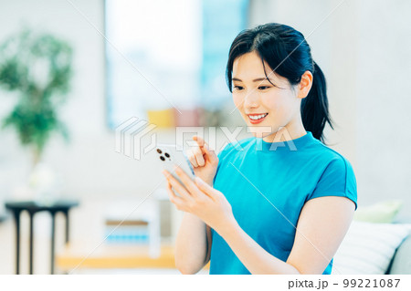リビングでスマートフォンを操作する若い女性 99221087