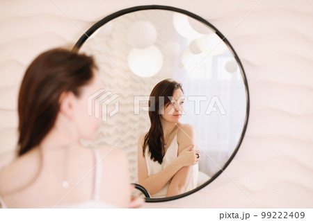 Portrait of calm pretty girl. Portrait of the woman reflected in mirror in a cozy light room in the morning.  99222409