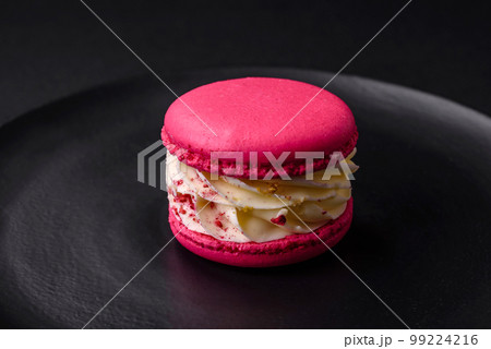 Beautiful tasty macaron with filling and fruit flavor on a black plate Beautiful tasty macaron with filling and fruit flavor on a black plate 99224216