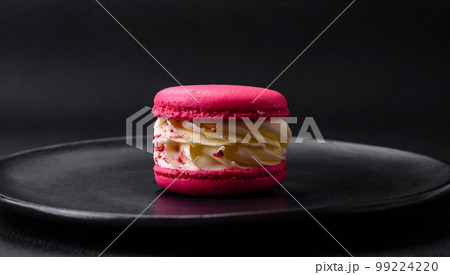 Beautiful tasty macaron with filling and fruit flavor on a black plate Beautiful tasty macaron with filling and fruit flavor on a black plate 99224220