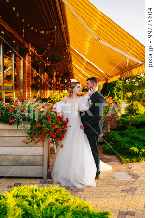 the bride and groom embrace on the terrace in the park near the restaurant. the bride and groom embrace on the terrace in the park near the restaurant. 99225604