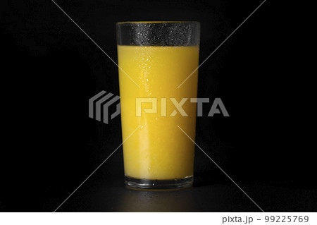 A glass of fresh orange juice on a black background, close-up A glass of fresh orange juice on a black background, close-up 99225769