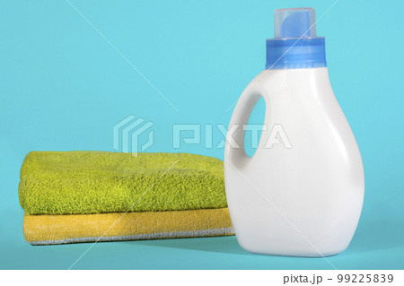 White plastic bottle of detergent and clean towels on a blue background 99225839