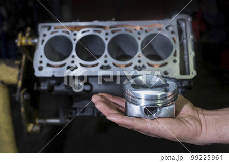 Engine cylinder in the hand of a mechanic. Car service. Auto repair concept Engine cylinder in the hand of a mechanic. Car service. Auto repair concept 99225964