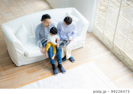 ソファでパソコンを見るファミリー　 99226473