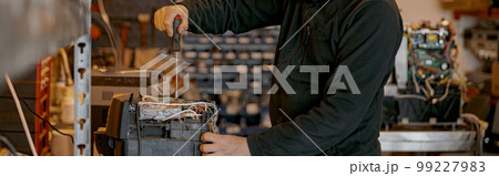 Repairman with screwdriver fixing coffee machine at table indoors Repairman with screwdriver fixing coffee machine at table indoors 99227983