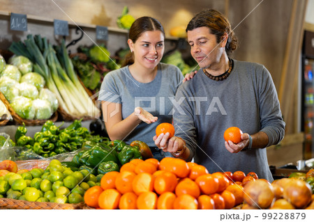 Man and woman choose tangerines and cauliflower in shop 99228879