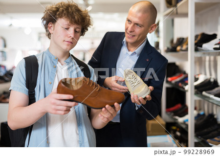 Man and teenage boy choosing dress shoes in shoe boutique 99228969