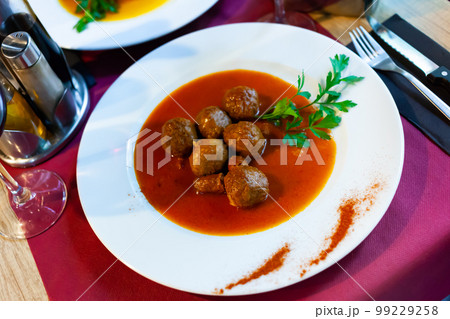 Pamplona cuisine meatballs and Navarra chistorra served with parley on plate on wooden table 99229258