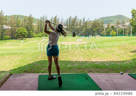 sian golfer woman swing golf ball practice at golf driving range for relax and healthy care port. 99229986