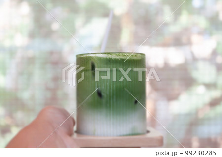 Hand holding iced matcha greentea Hand holding iced matcha greentea 99230285