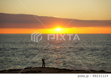 美しい夕日(朝日)と釣りをする男性のシルエット 99231124