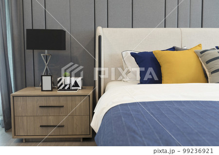 A large double bed with pillows and a bedspread. Lamps with lampshades on the bedside tables.  99236921
