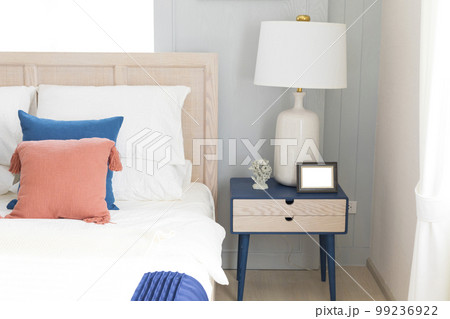 A large double bed with pillows and a bedspread. Lamps with lampshades on the bedside tables.  99236922