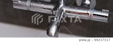 Chrome faucets on white ceramic bathtub in bathroom Chrome faucets on white ceramic bathtub in bathroom 99237317