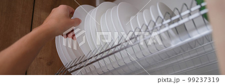 Woman graceful hand takes out clean plate from cupboard Woman graceful hand takes out clean plate from cupboard 99237319