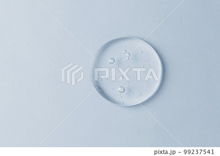 Cosmetic lotion transparent gel drop texture, on blue background Cosmetic lotion transparent gel drop texture, on blue background 99237541