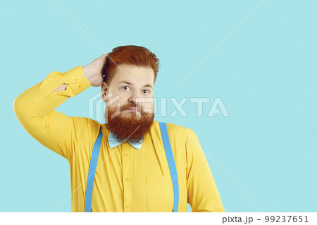 Fat man isolated on turquoise background scratches head with funny confused face expression 99237651