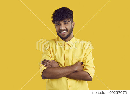 Young ethnic Indian man in stylish shirt smiling broadly posing with arms crossed over chest 99237673