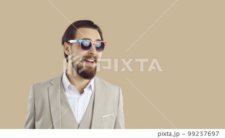 Handsome young American man in suit and sunglasses on beige copy space background 99237697
