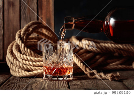 Rum, cognac, or whiskey is poured into a crystal glass. Rum, cognac, or whiskey is poured into a crystal glass. 99239130