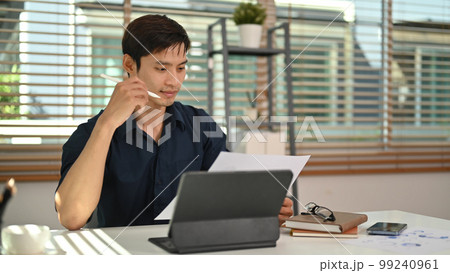 Smart businessman reading reports, working on financial and marketing project at modern home office Smart businessman reading reports, working on financial and marketing project at modern home office 99240961