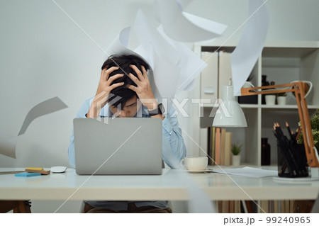Stressed man office worker sitting at desk with falling paperwork, feeling distressed anxious with work deadline Stressed man office worker sitting at desk with falling paperwork, feeling distressed anxious with work deadline 99240965