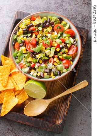 Cowboy texac caviar is a traditional American salad made with black beans, garlic, onion, bell peppers, jalapenos, corn, coriander closeup in the bowl. Vertical top view Cowboy texac caviar is a traditional American salad made with black beans, garlic, onion, bell peppers, jalapenos, corn, coriander closeup in the bowl. Vertical top view 99242295