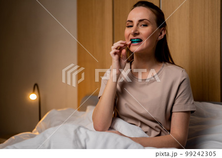 An attractive woman uses a multifunctional trainer at night, before going to bed. They help to align the growing teeth and correct the bite. Corrects the position of the tongue An attractive woman uses a multifunctional trainer at night, before going to bed. They help to align the growing teeth and correct the bite. Corrects the position of the tongue 99242305
