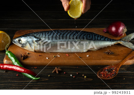 The cook presses fresh lemon juice on raw mackerel fish or scomber with hand before cooking with ingredients and fragrant spices. The cook presses fresh lemon juice on raw mackerel fish or scomber with hand before cooking with ingredients and fragrant spices. 99243931