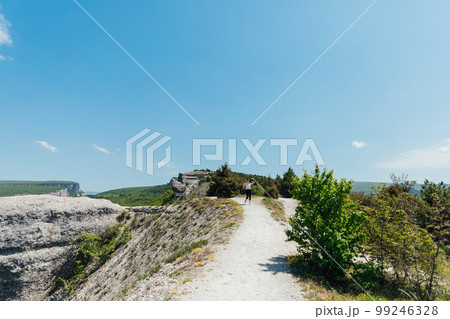 a woman in sportswear walks down the road on a hiking trip 99246328