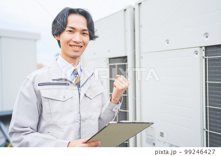 オフィスビルの屋上で業務用エアコンの室外機を点検する若いエンジニアの男性 オフィスビルの屋上で業務用エアコンの室外機を点検する若いエンジニアの男性 99246427