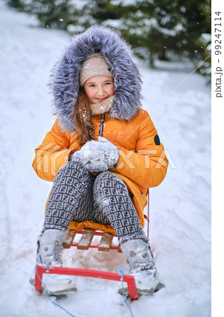 Child sledding, sits on a sled and throws snow. Child sledding, sits on a sled and throws snow. 99247114