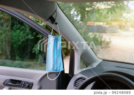The medical mask hangs on the rearview mirror inside the car. Coronavirus Covid-19. Pandemic. The medical mask hangs on the rearview mirror inside the car. Coronavirus Covid-19. Pandemic. 99248089