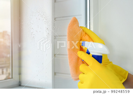 Female hands in yellow rubber gloves wash the windows. Cleaning concept 99248559