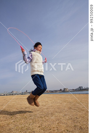 冬の海岸の公園で縄跳びをしている小学生の女の子の様子 99250009