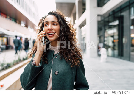 Young woman talking on mobile phone while walking in the city 99251875