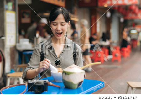 Happy young Asian woman backpack traveler enjoying street food at China town street food market in Bangkok, Thailand. Traveler checking out side streets. 99252727
