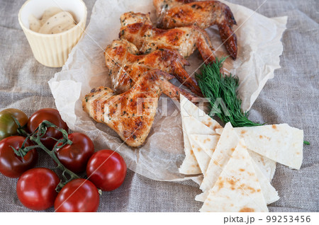 Ready spicy grilled chicken wings with greens and tomato 99253456