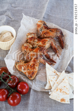 Ready spicy grilled chicken wings with greens and tomato 99253457