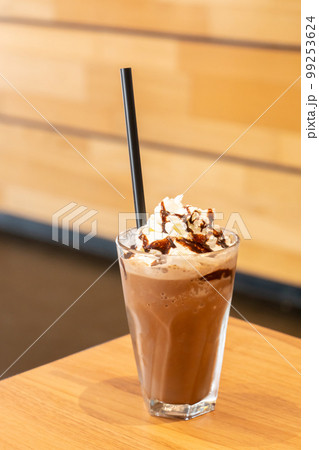 Frappuccino with straw in plastic takeaway cup on white wooden table 99253624