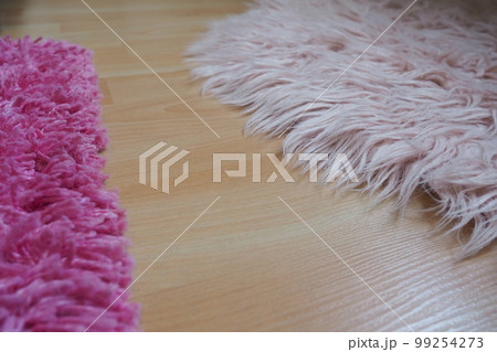 Long pile rug in pink on a beige laminate floor. Feminine interior for a room or bedroom of a girl or woman. Interior design in pink tones. Flooring is laminate. The role of dust mites in allergies. Long pile rug in pink on a beige laminate floor. Feminine interior for a room or bedroom of a girl or woman. Interior design in pink tones. Flooring is laminate. The role of dust mites in allergies. 99254273