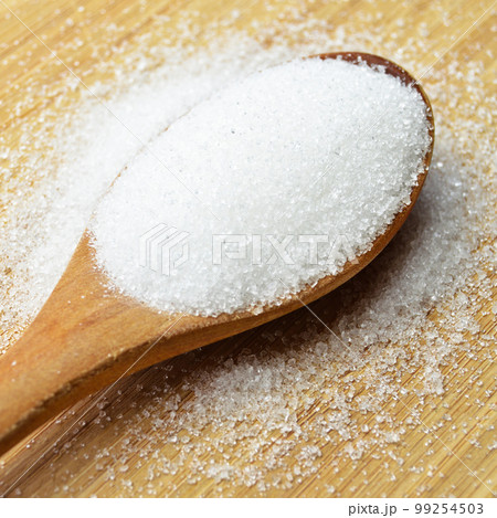 Granulated sugar in wooden spoon on bamboo cutting board, on bamboo cutting board Granulated sugar in wooden spoon on bamboo cutting board, on bamboo cutting board 99254503
