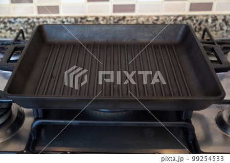 Empty black cast iron grill pan on gas stove in a modern kitchen 99254533