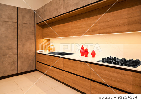 Modern brown wood oak kitchen cabinet equipment, granite black sink and glass gas stove in a home 99254534